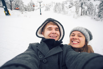 Fototapeta na wymiar Young and happy couple doing winter selfie outdoor. Christmas, New Year and people concept