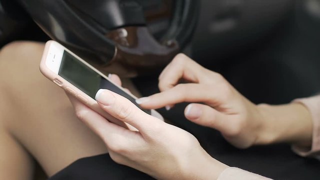 Business woman scrolling social media, sitting in car with gadget in hands