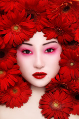 Young beautiful asian girl with pink make-up and red flowers around her face