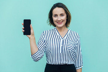 Success and beautiful business woman showing new smart phone and looking at camera with toothy smile.