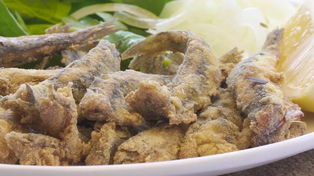 Turkish Hamsi Tava with lemon and arugula. Fried Anchovies close up view.