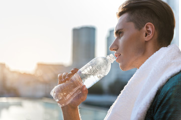 Serene male athlete drinking bottle of water