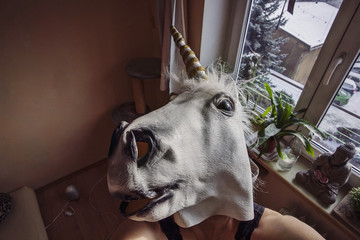 Girl wearing Unicorn mask in her home environment, taking selfie