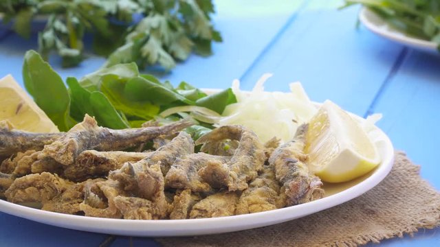 Turkish Hamsi Tava with lemon and arugula. Fried Anchovies close up view.