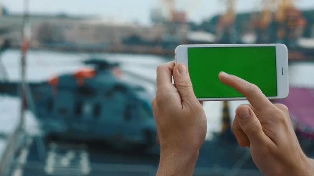Closeup male man hands holding using modern white smart phone mobile green screen chromakey touching tapping blurred helicopter background horizontal keeping outside digital device internet app 3g