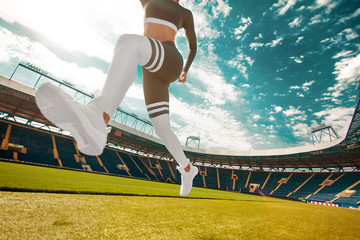 Young fitness woman runner athlete legs running at stadium. Sport and health concept.