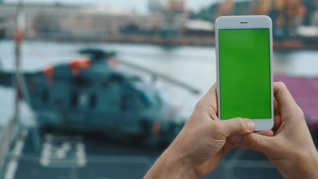 Closeup man hands holding using white smartphone mobile green screen chroma key touching tap blur helicopter background vertically position digital device networking app 3g connection lifestyle