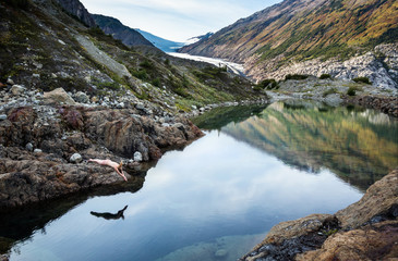 Young woman skinny dipping in calm pool in the Canadian mountains