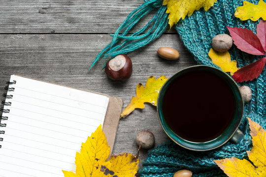 Autumn background with dry leaves, scarf, cup of coffee and blank notebook