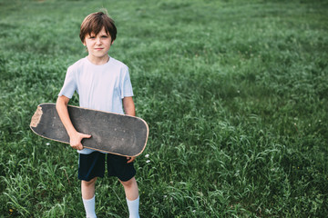 Creative portrait of a boy with old skateboard in the park. © BestForYou