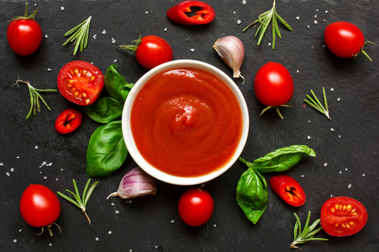 Tomato ketchup sauce in a bowl with spices, herbs and cherry tomatoes