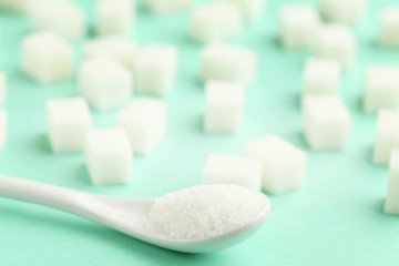 Fototapeta na wymiar Sugar cubes with white spoon on mint background