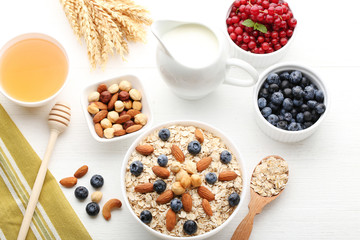 Oat flakes with berries, honey, milk and nuts on wooden table