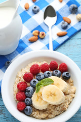 Oatmeal in plate with berries on wooden table