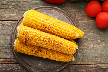 Tasty grilled corns on grey wooden table