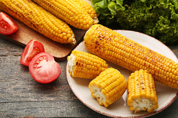 Tasty grilled corns with tomatoes on grey wooden table