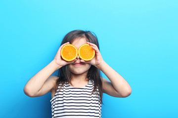 Beautiful little girl with orange on blue background