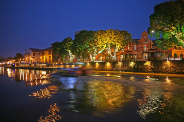 Elegant beautiful riverside views as a boat passes at dusk in Melaka, the UNESCO World Heritage Site, Malaysia