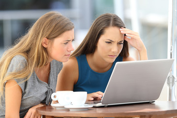 Two worried friends watching media content on line