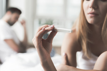 Thoughtful girl undergoing pregnancy test near boyfriend