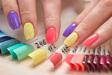 Obraz na płótnie Canvas Beautiful summer manicure on female fingers. Womans fingers with bright varnished nails, nails samples variety. Professional salon of beauty and spa.