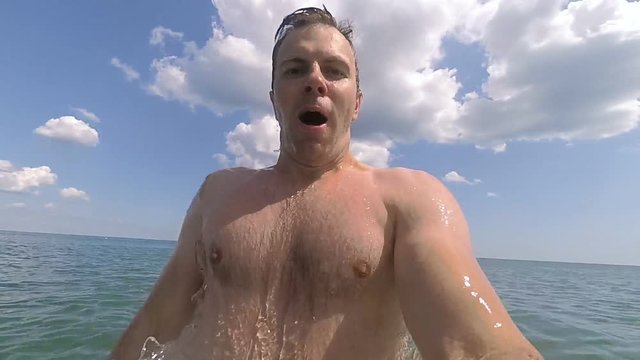 Young athletic man making selfie in the sea and diving under water in slow motion