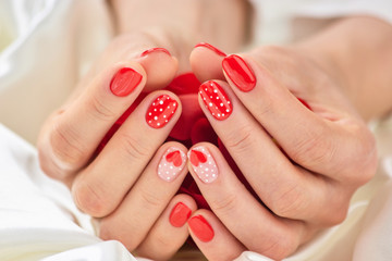 Female manicure on Valentine Day. Female hands with beautiful manicure holding rose petals. Nail design on Valentine Day. - obrazy, fototapety, plakaty