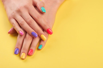 Female hands with summer manicure. Teen girl hands with bright summer manicure on yellow...