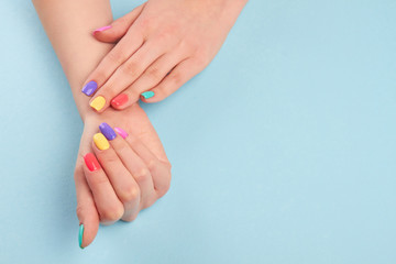 Hands with short manicured nails. Manicure covered with nail polish in summer colors. Girls manicured hands and copy space.