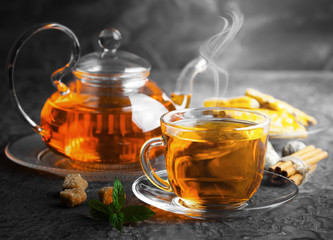 Tea in a cup on a metallic background in a composition with a cookware
