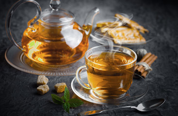 Tea in a cup on a metallic background in a composition with a cookware