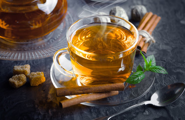 Tea in a cup on a metallic background in a composition with a cookware