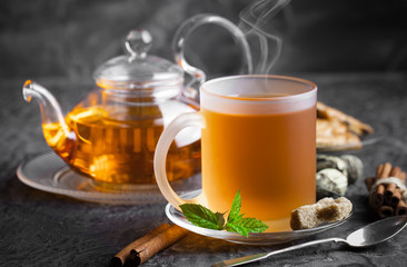 Tea in a cup on a metallic background in a composition with a cookware