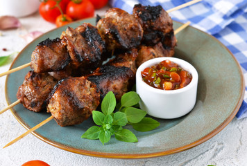 Homemade pork shish kebab with tomato sauce on a concrete background
