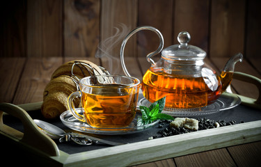 Tea in a cup on a metallic background in a composition with a cookware