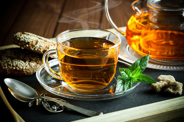 Tea in a cup on a metallic background in a composition with a cookware