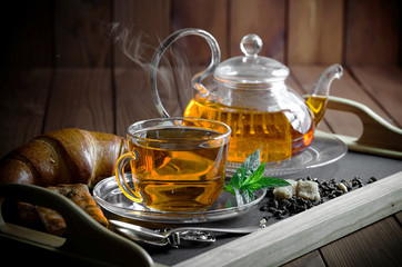 Tea in a cup on a metallic background in a composition with a cookware