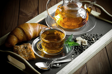 Tea in a cup on a metallic background in a composition with a cookware