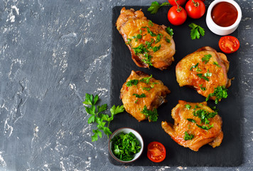 Chicken thighs baked with pesto and tomato sauce on a slate board