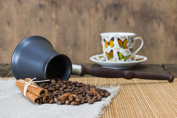 Coffee beans in a ring of hemp, cinnamon,star anise and nutmeg on a background of a wooden table. Roasted coffee bean background close up.