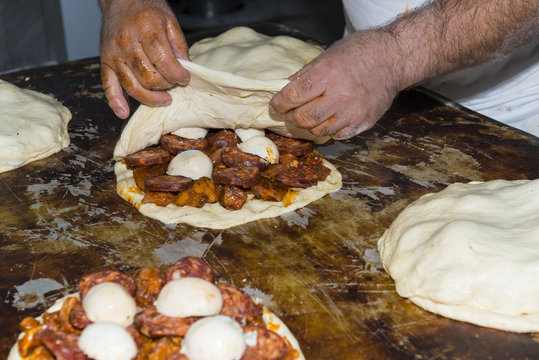 Trabajador preparando hornazos o empanadas de carne y huevo tradicionales en la panadería
