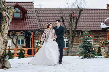 Obraz premium The bride and groom are walking in the winter park. Wedding in the winter.