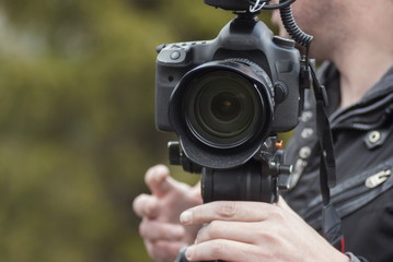 Man recording with camera outdoor at natural background
