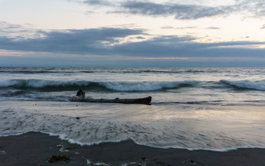Sunset on ocean shore waves on water.