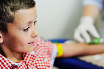 a doctor or nurse takes blood from a vein in a child of a boy. Blood chemistry