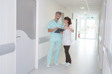 medical staff looking at clipboard in hospital corridor