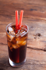 Close up on a cold refreshing soft drink with ice on a dark wooden background