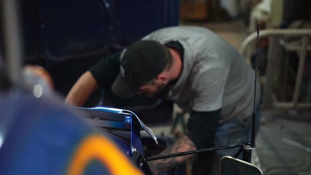 Mechanic in the cap is repairing the car