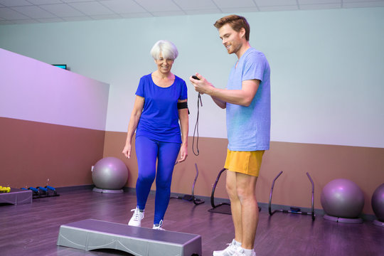 coach timing the elderly woman on doing the stepper