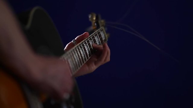 Musician performer with an acoustic guitar playing solo very close-up